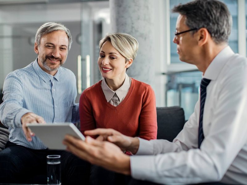 happy-mid-adult-couple-using-touchpad-with-their-financial-consultant-in-the-office-1.jpg